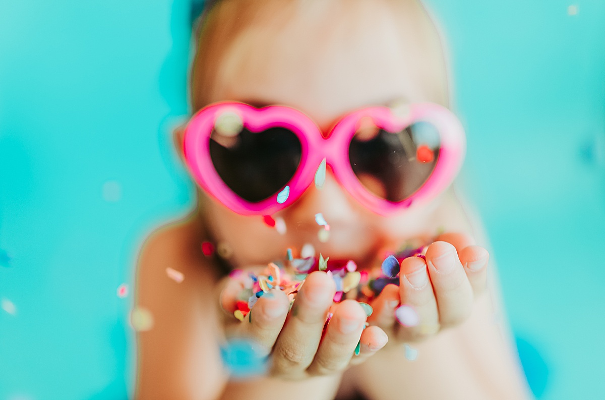 Child with heart glasses blowing confetti