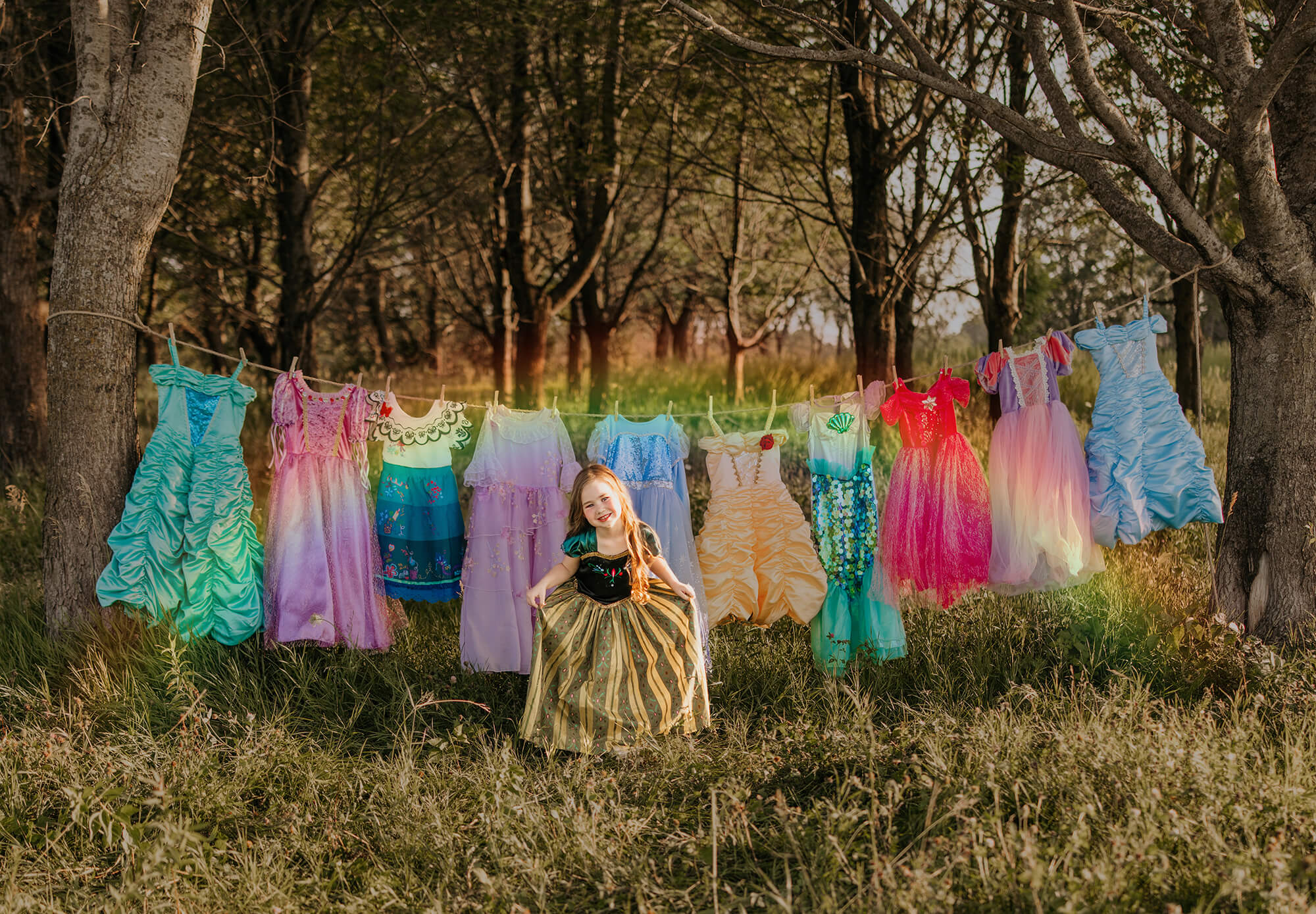 Girl in forest with colorful dresses hanging